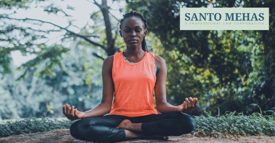 Woman sitting with legs crossed outside with hands on knees.
