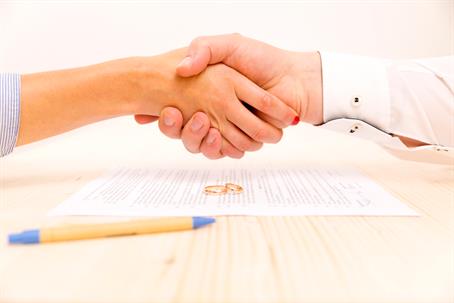 couple shaking hands after signing divorce papers